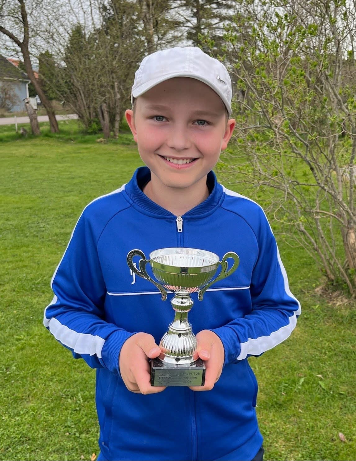 Ung tävlingsspelare med pokal utomhus